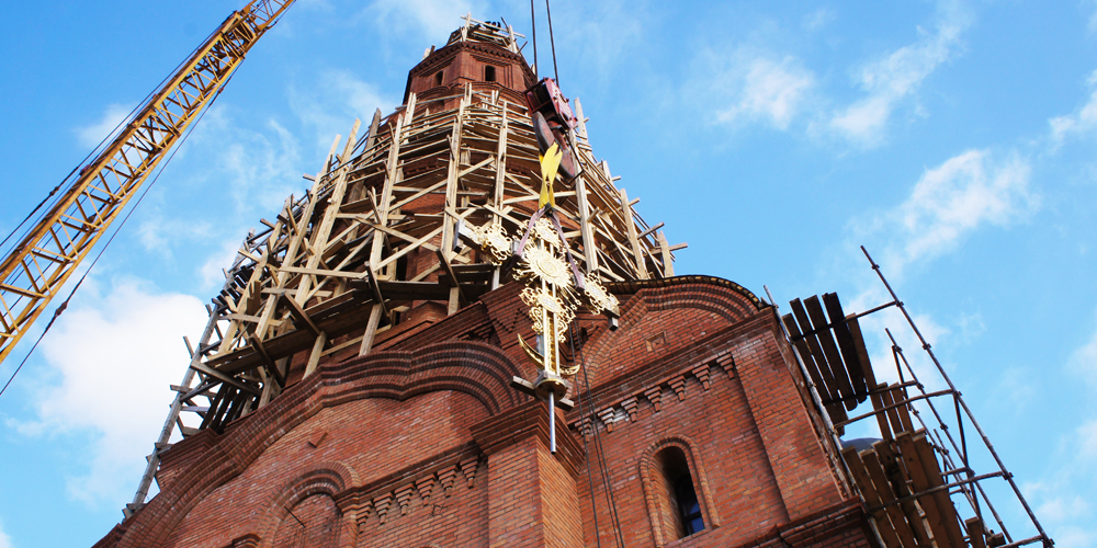 На возведенную колокольню Успенского собора поднимается крест
